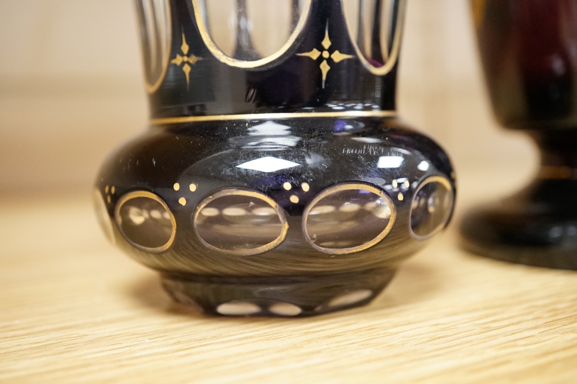 A 19th century Bohemian engraved ruby glass goblet, a similar amethyst and clear overlaid glass vase and an enamelled amethyst glass goblet, largest 15cm high